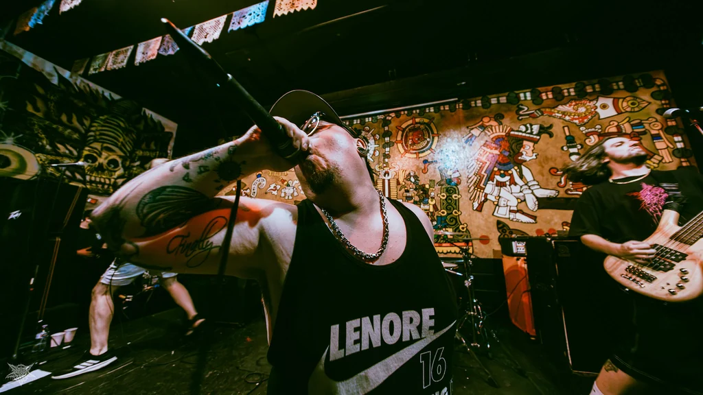 Demsfightingwords vocalist and bassist performing in a packed, mural-lined venue